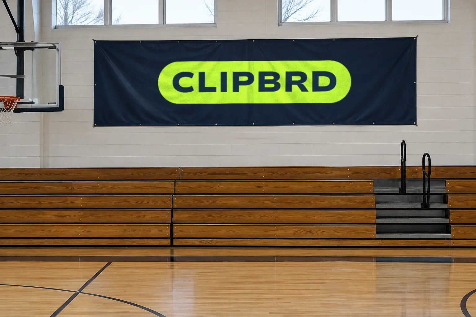A navy vinyl banner with the lime Clipbrd pill logo hanging above gym bleachers