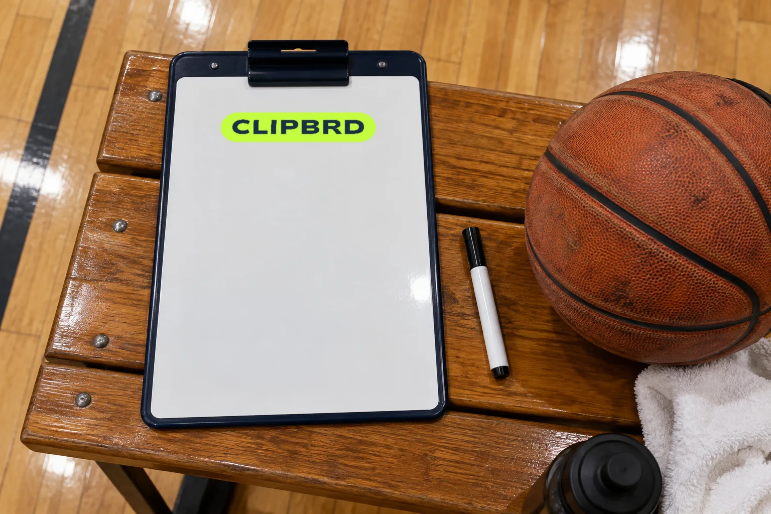 A coach’s dry-erase clipboard with the lime Clipbrd wordmark on a gym bench, beside a marker and a basketball