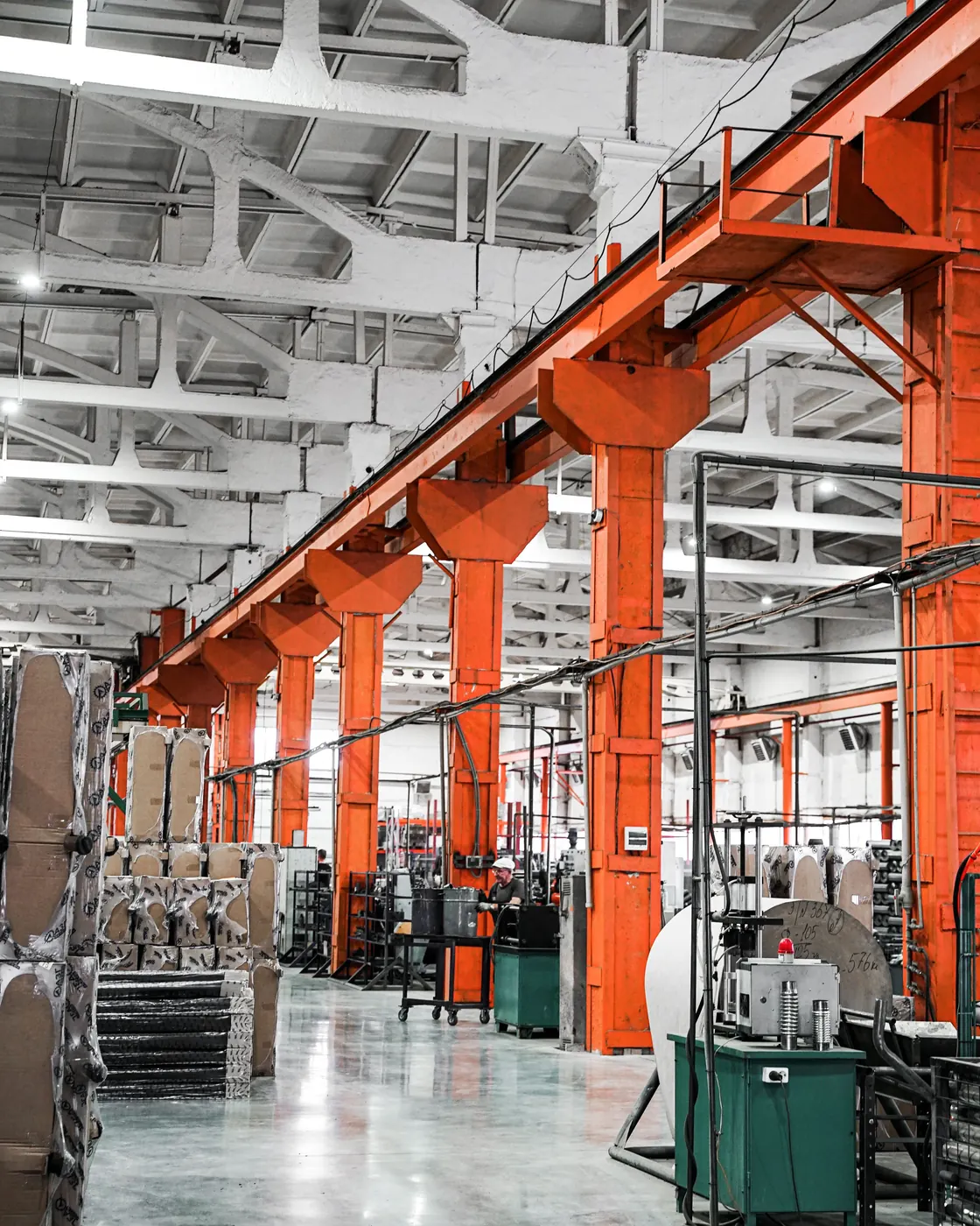 The floor of a manufacturing plant, orange crane rails running the length of the building