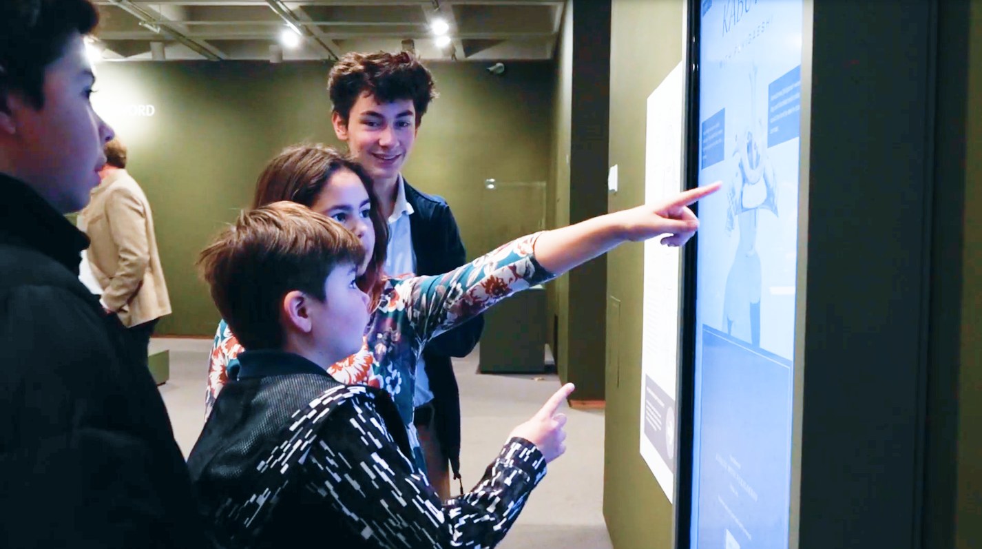 A group of kids discovering the touchscreen and pointing at the armor select