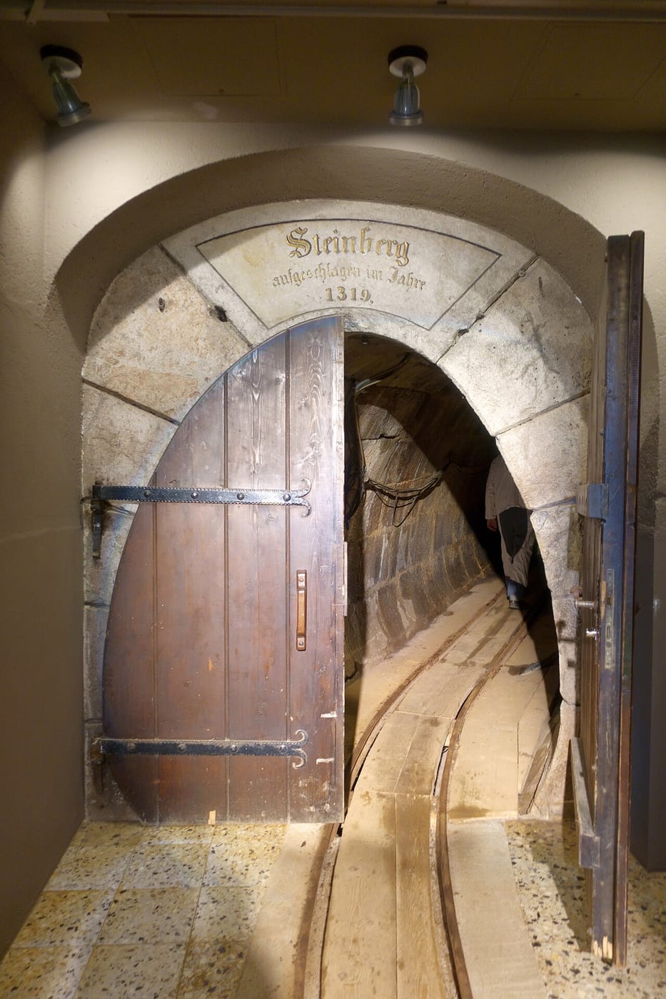 Arched wooden entrance to the Steinberg tunnel at Altaussee, with rails leading into the darkness.